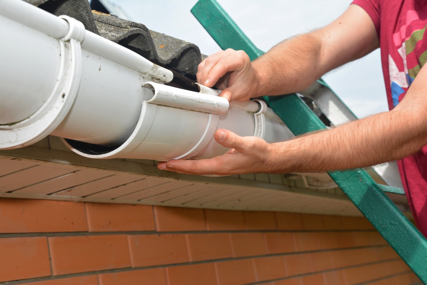 Gutter pipeline installation. Roofer contractor installing and repair rain gutter. Guttering repair with contractor hands.